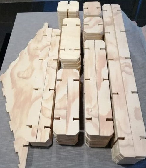 A full set of Play Planks stacked by size, showing the notched plywood pieces